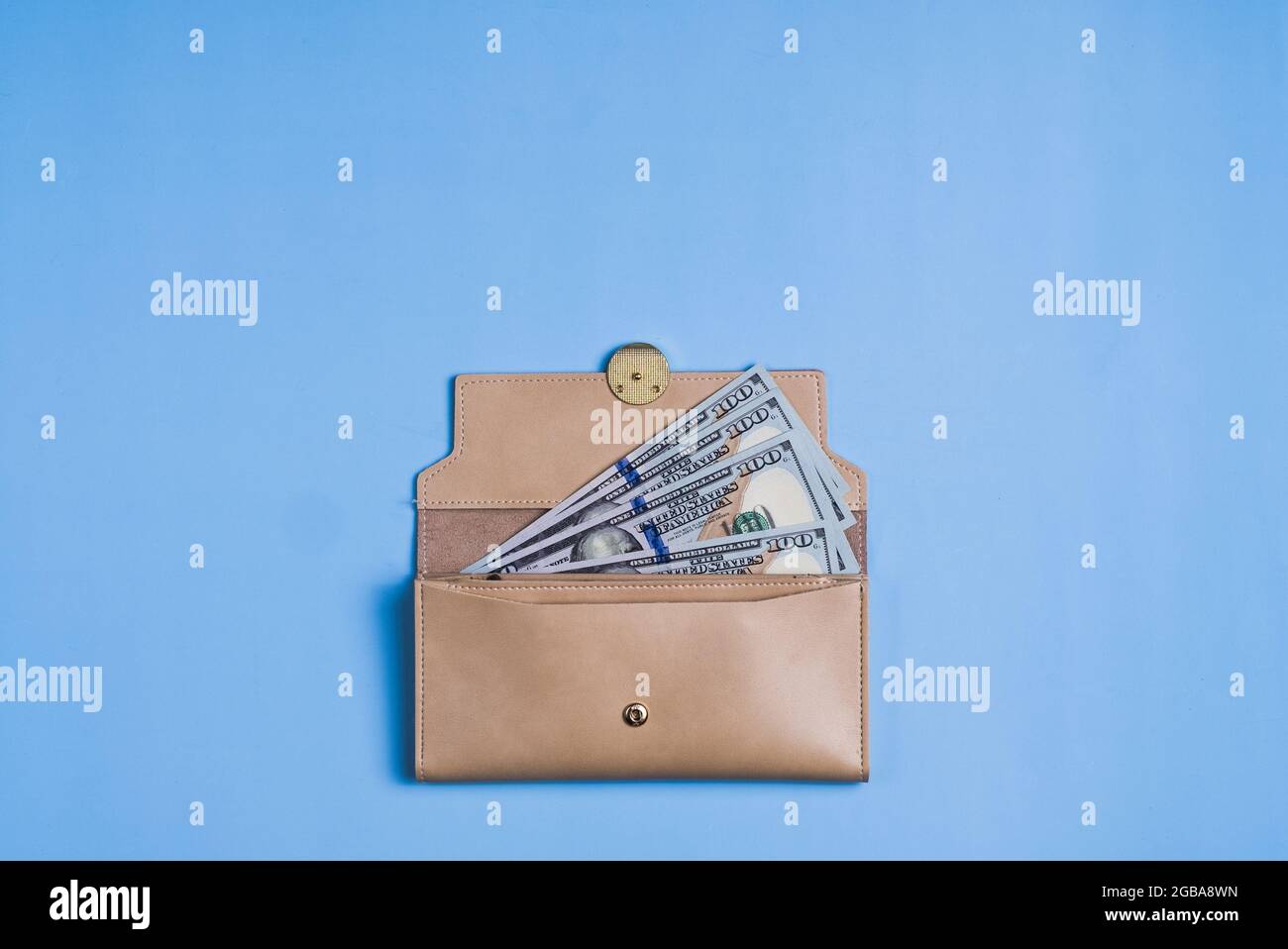 Banconote da 100 dollari con e portafoglio su sfondo blu. Foto Stock