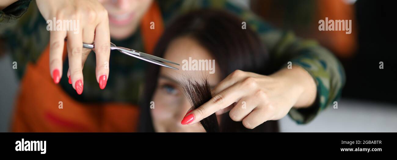 Donna parrucchiere taglia le punte del cliente in salone di bellezza Foto Stock