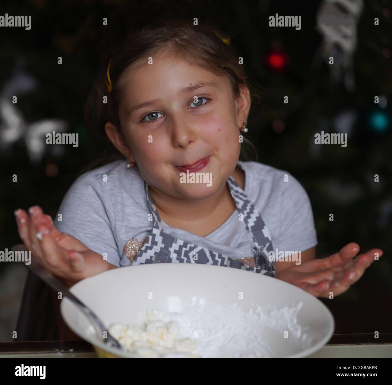 Smiling Girl prepara l'impasto dei biscotti e guarda la macchina fotografica. Concetto di vacanza per famiglie. Pasqua, Natale, Festa della mamma, concetto di cottura di Capodanno Foto Stock