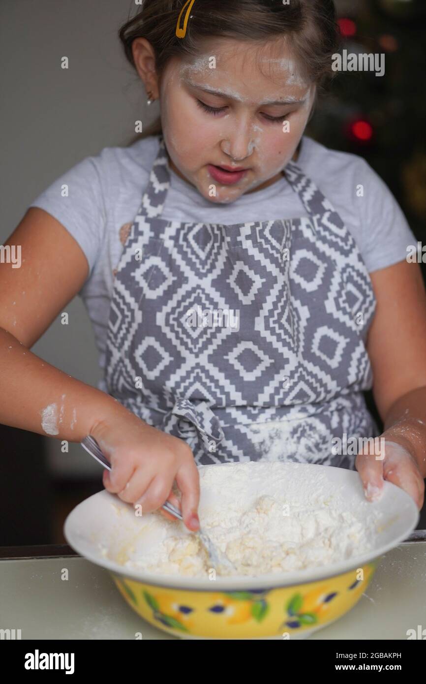 La ragazza cuoce l'impasto dei biscotti. Mescola burro, zucchero in polvere e farina. La ragazza si è cosparsa di farina. Vacanza in famiglia. Natale, Pasqua, Capodanno cottura. Foto Stock