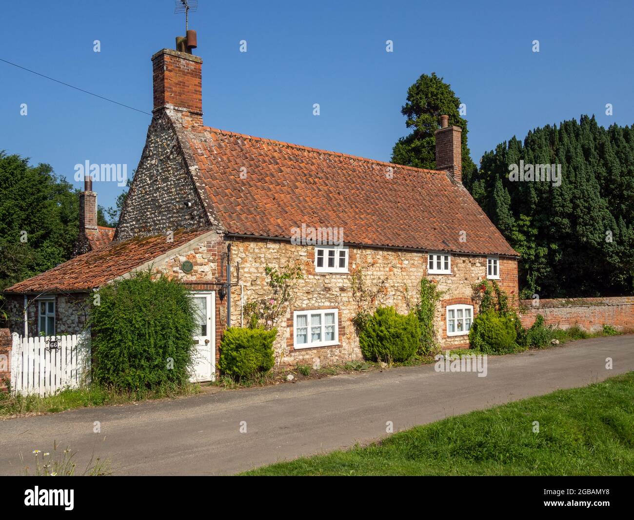 Idilliaca scena villaggio inglese in estate, con un vecchio cottage in pietra del 15 ° secolo; Old Hunstanton, Norfolk, Regno Unito Foto Stock