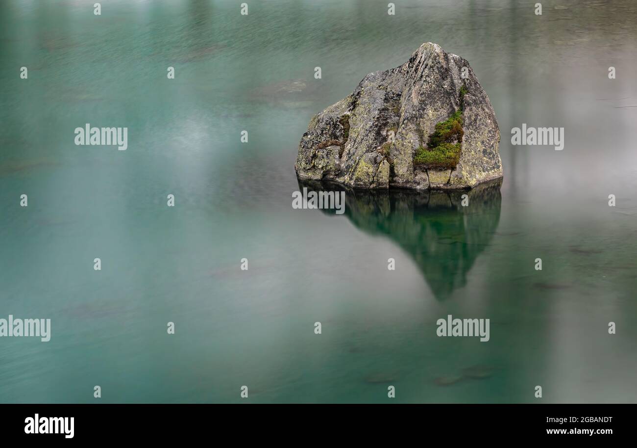 Lunga padronanza di una roccia nel lago di montagna passo Julierpass in Svizzera Foto Stock