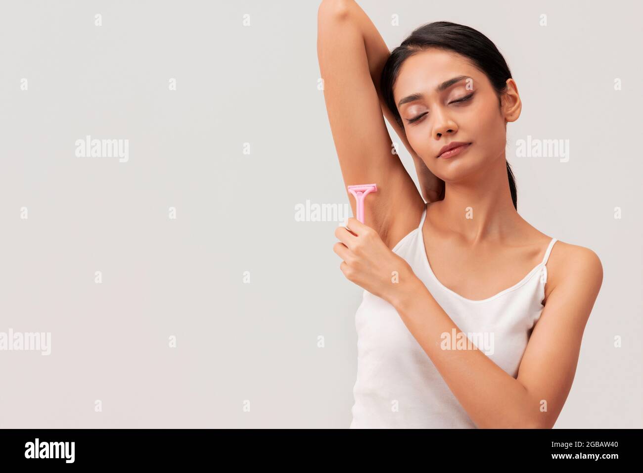 Una giovane donna che usa il rasoio per la rimozione dei capelli sulle ascelle. Foto Stock