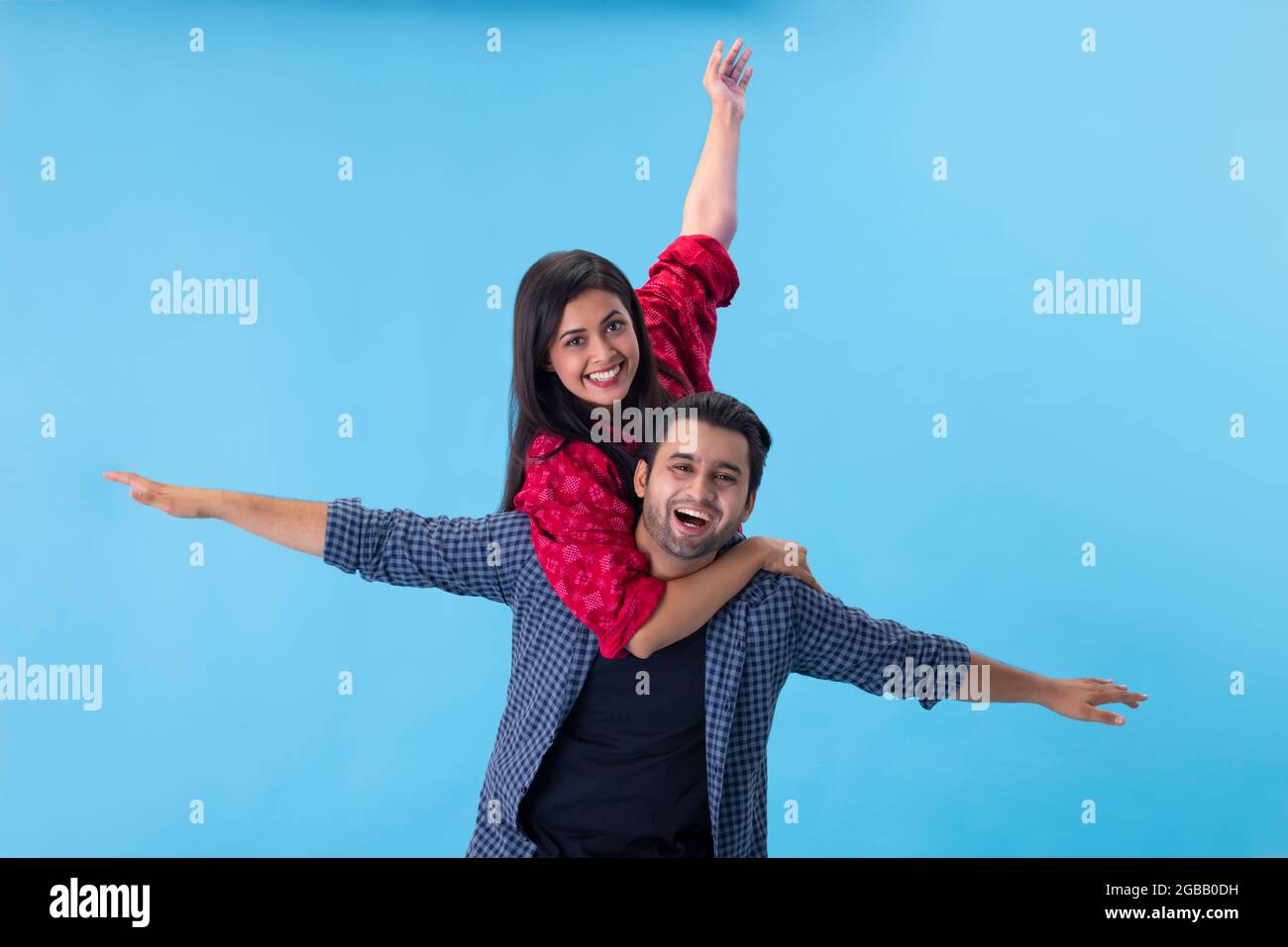 Una giovane coppia che colpisce una divertente posa con le braccia estese verso l'alto e lateralmente. Foto Stock