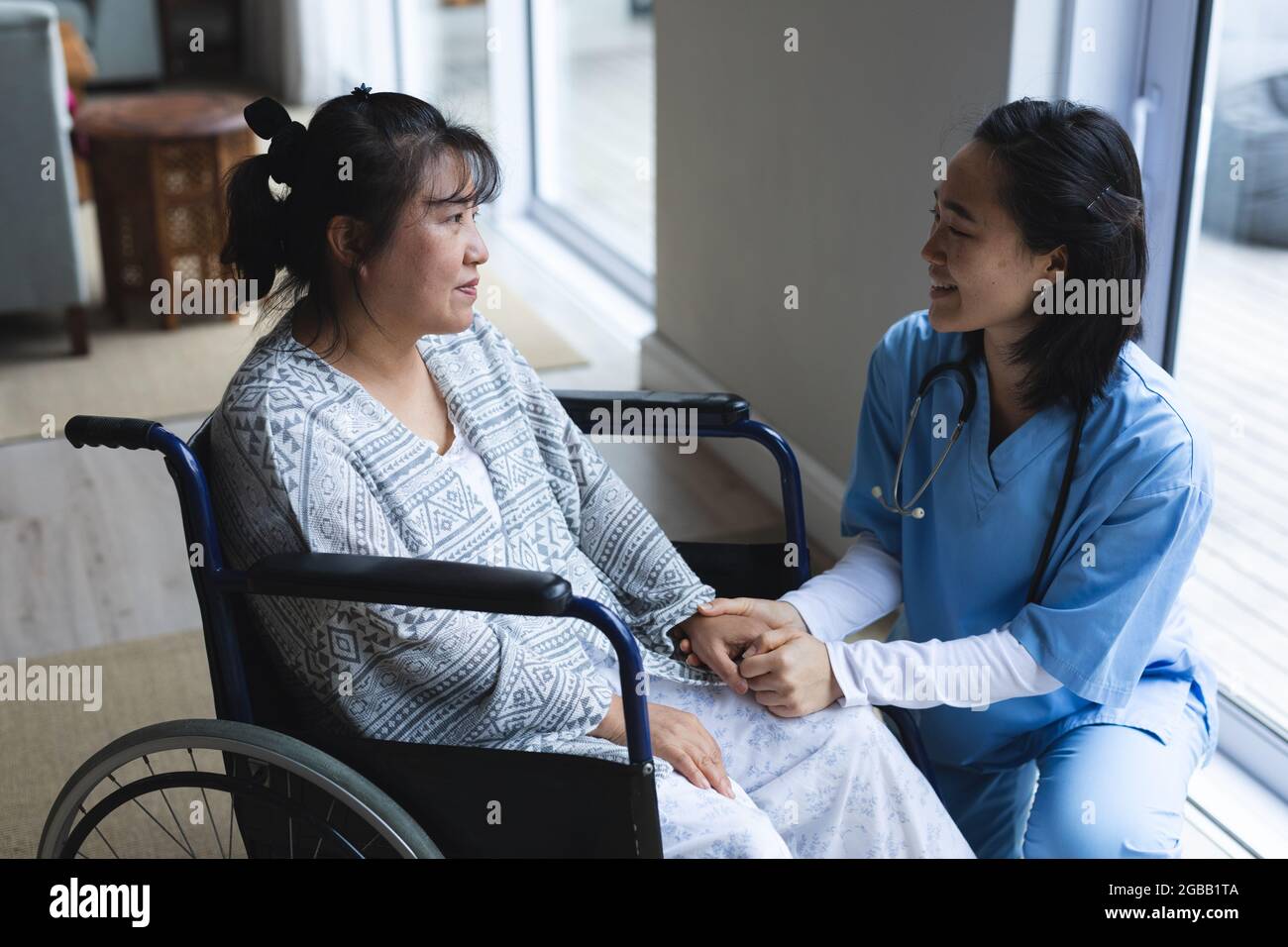 Fisioterapista femminile asiatica che cura la paziente femminile asiatica a casa sua Foto Stock