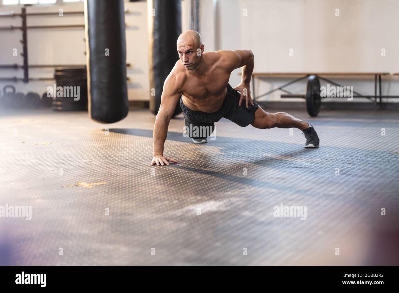 Forte uomo caucasico che si esercita in palestra, facendo push-up con una mano Foto Stock