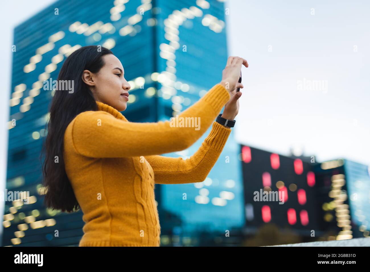 Donna asiatica che scatta foto con smartphone in strada Foto Stock