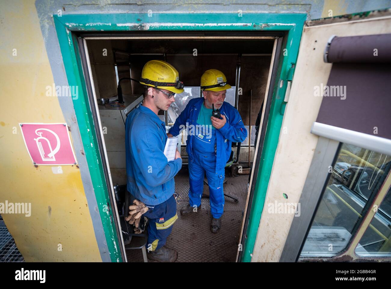 08 luglio 2021, Sassonia, Neukieritzsch: Marvin Kanitz (l) e Frank Scheer, minatori dell'opencast Vereinigtes Schleenhain, parlano nel taxi del conducente di una macchina da miniera. Scheer imparò il suo commercio presso l'ex legnite Combine nel 1980, e il 59-anno-vecchio andrà in pensione a gennaio. È uno dei 435 dipendenti di Mibrag che lascerà l'azienda entro l'inizio del 2022. Kanitz ha iniziato il suo apprendistato come operatore di macchine e impianti nella miniera di opencast nel 2015. Il giovane minatore di carbone pensa che in qualche modo continuerà per lui. Attualmente Mibrag lavora con 1700 dipendenti. Nel 2038, il carbone phase-out in Foto Stock