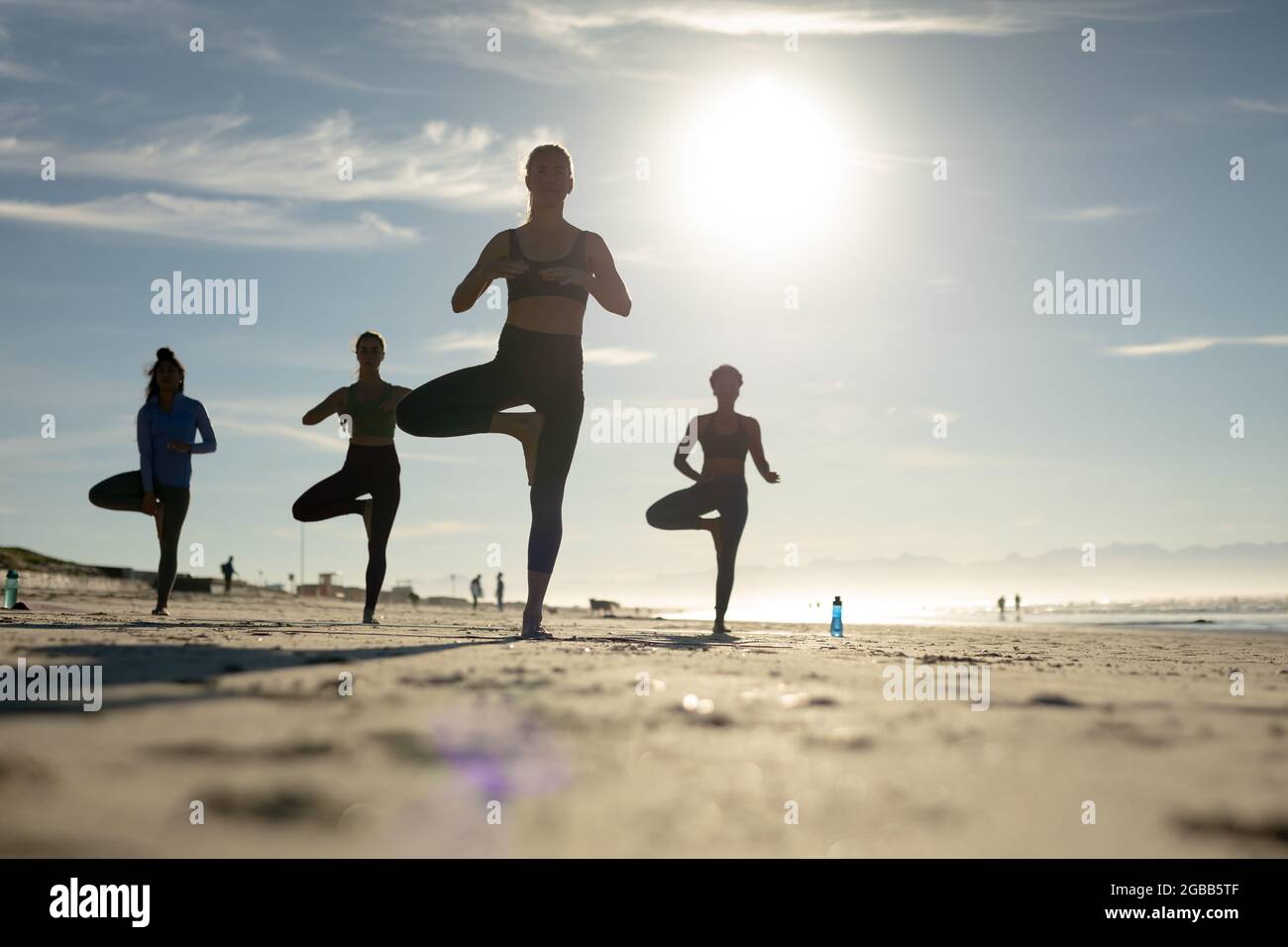 Gruppo di diverse amiche che praticano lo yoga in spiaggia Foto Stock