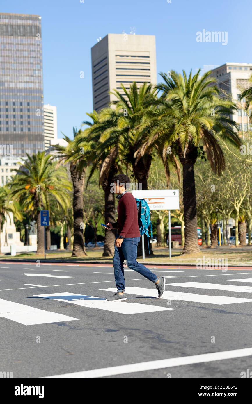 Uomo afro-americano in città con smartphone e a piedi Foto Stock