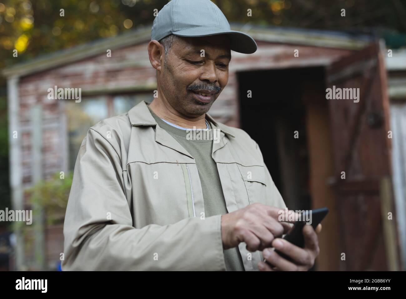 afroamericano giardiniere maschile utilizzando smartphone al centro giardino Foto Stock