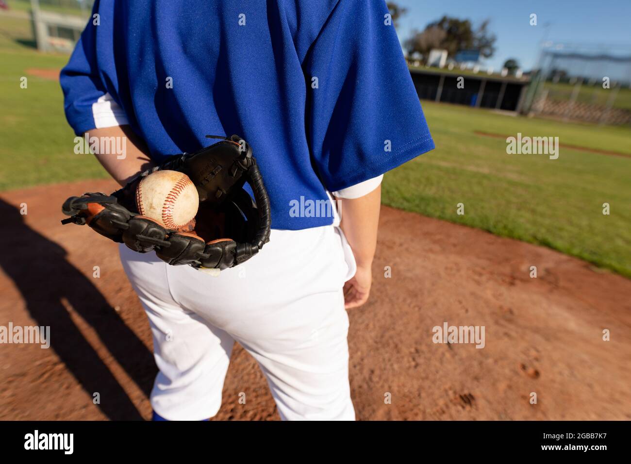 Midseccton di femmina da baseball lanciatore sul soleggiato campo da baseball che tiene la palla in guanto durante la partita Foto Stock