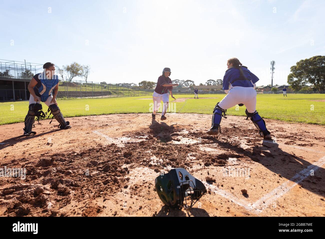 Gruppo vario di giocatori femminili di baseball in azione sul soleggiato campo da baseball durante la partita Foto Stock