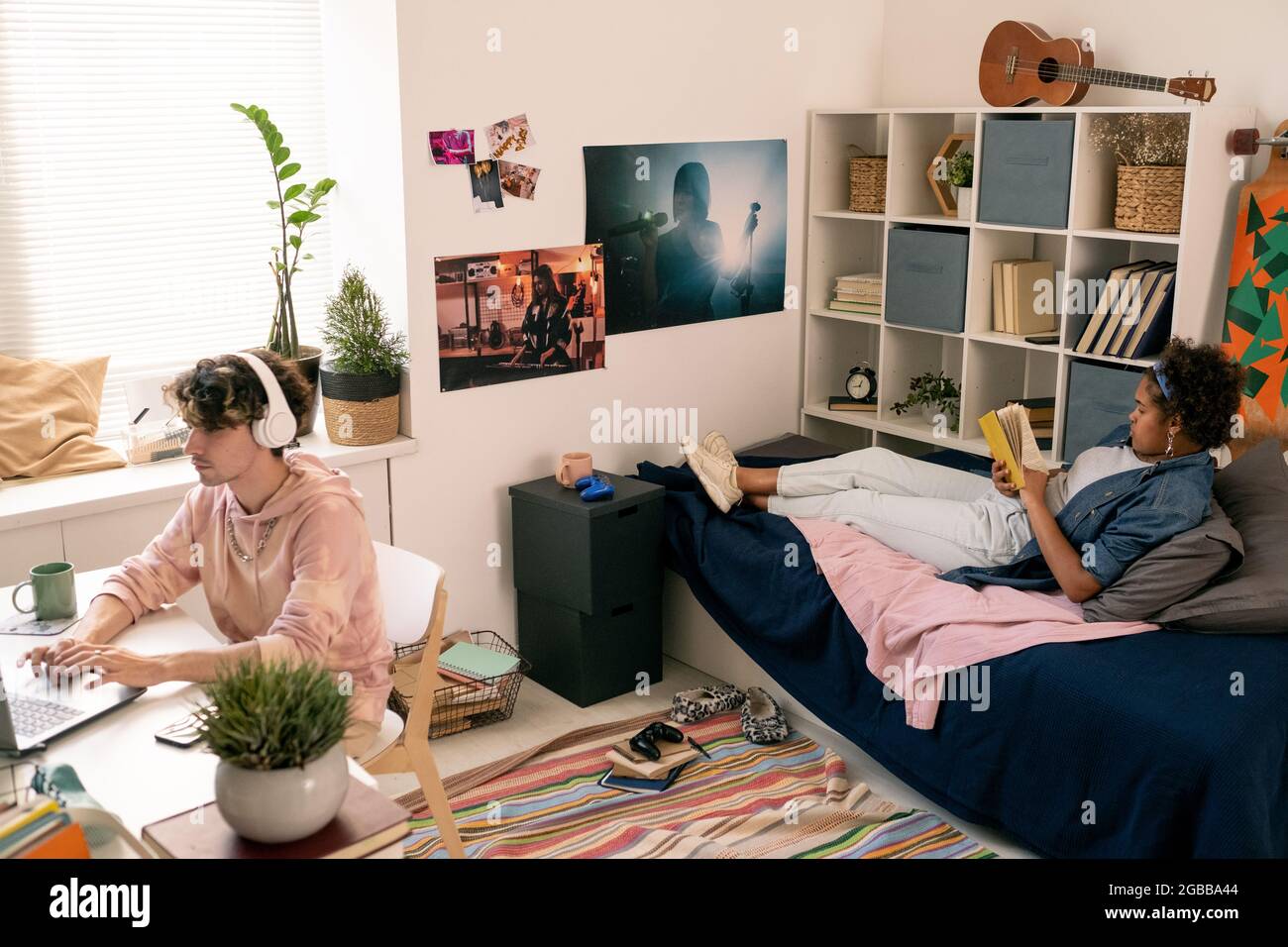 Due teenager riposanti contemporanei che leggono il libro e la rete in camera da letto Foto Stock