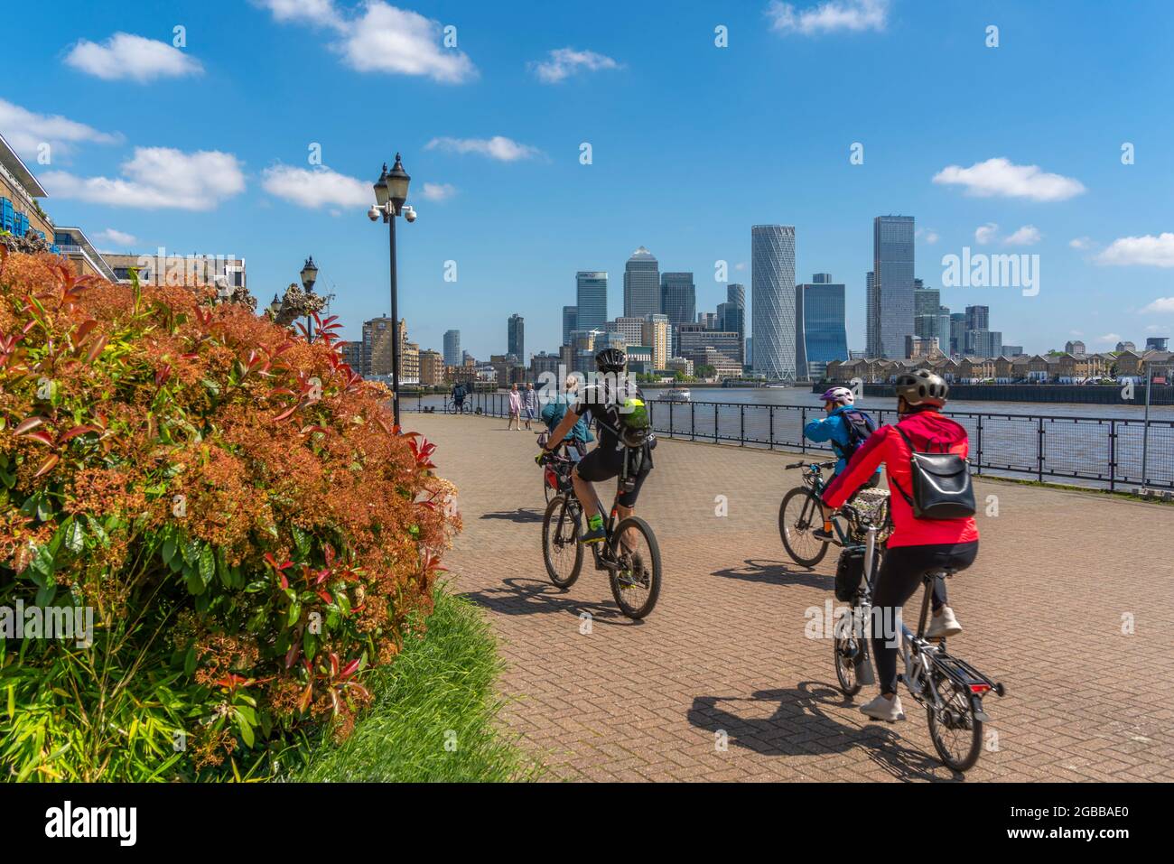 Vista dei ciclisti sul Tamigi Path a Wapping e Canary Wharf Financial District sullo sfondo, Londra, Inghilterra, Regno Unito, Europa Foto Stock
