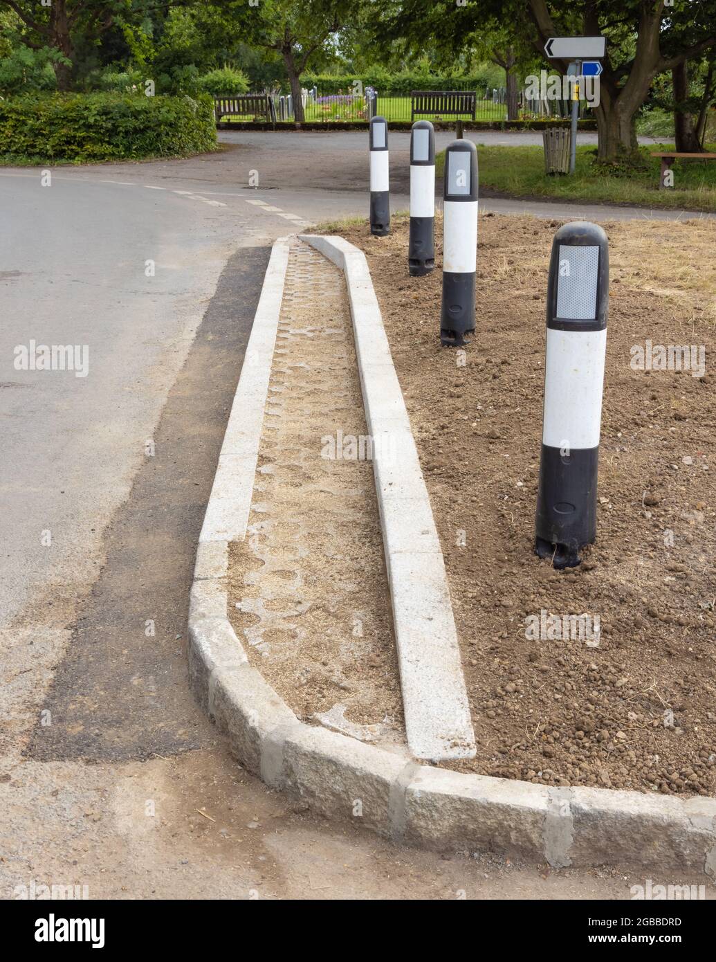 Marciapiede laterale appena posato su una falda erbosa con blocchi di protezione per erba appena seminati e montanti di segnalazione pericolo. REGNO UNITO Foto Stock