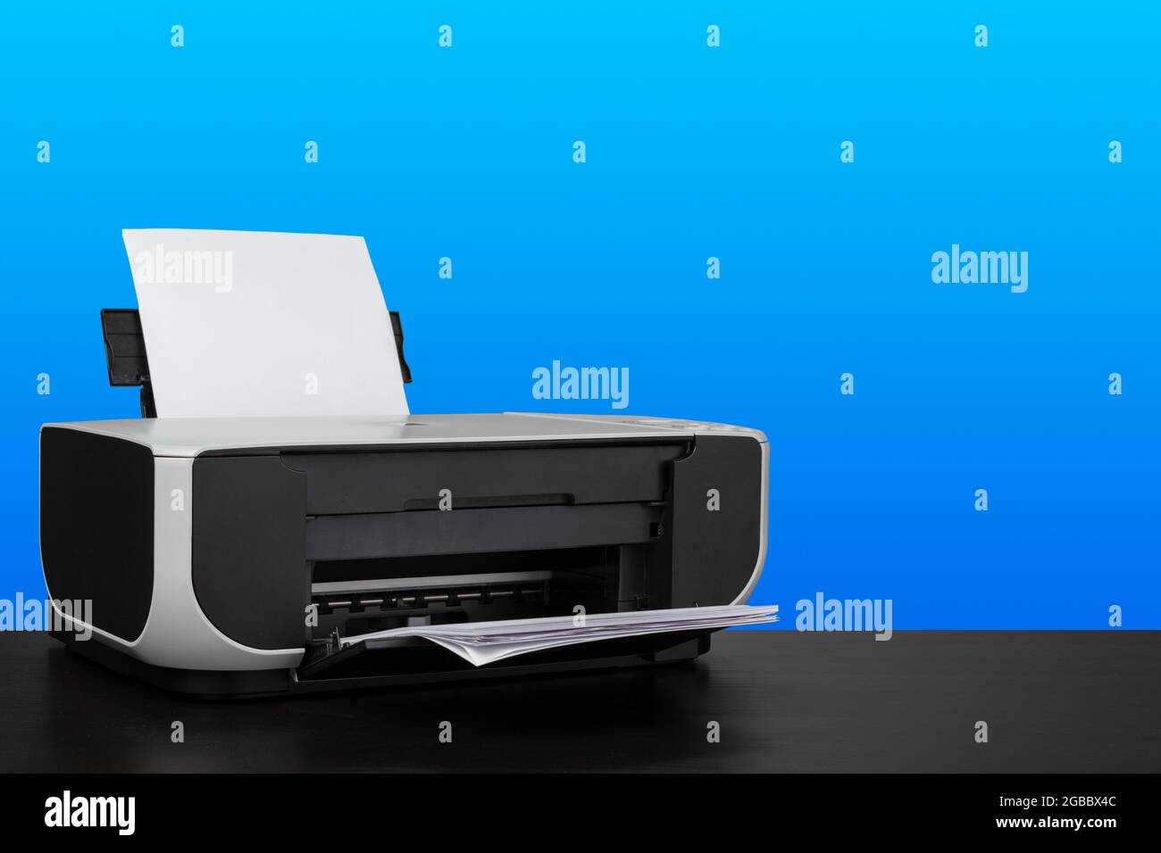 Stampante laser compatta su scrivania nera su sfondo blu Foto