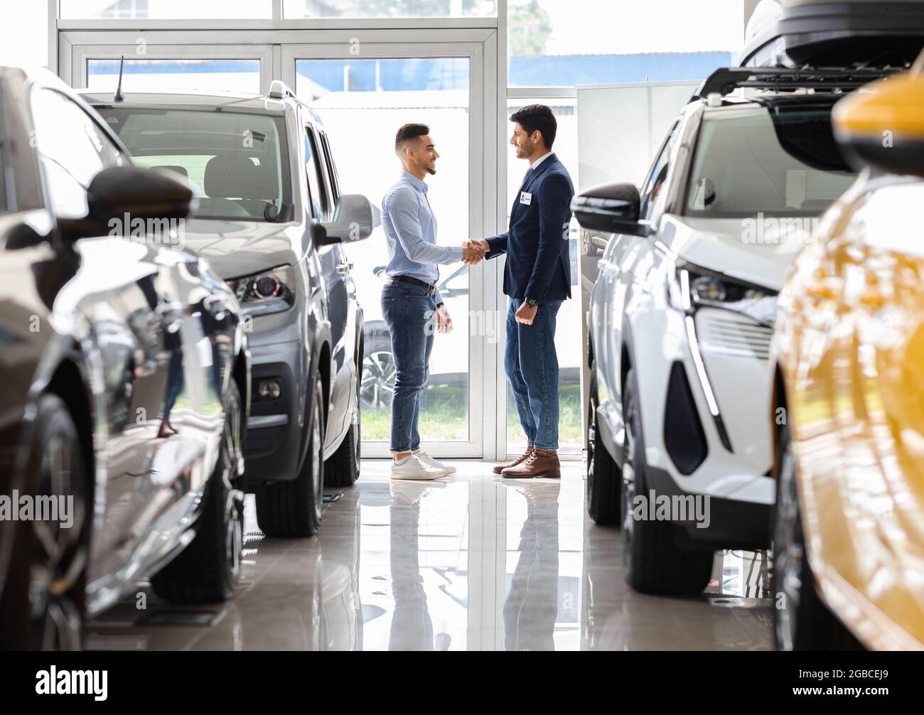 Uomo ricco medio-orientale scuotendo mano del responsabile di vendite nello showroom dell'automobile Foto Stock