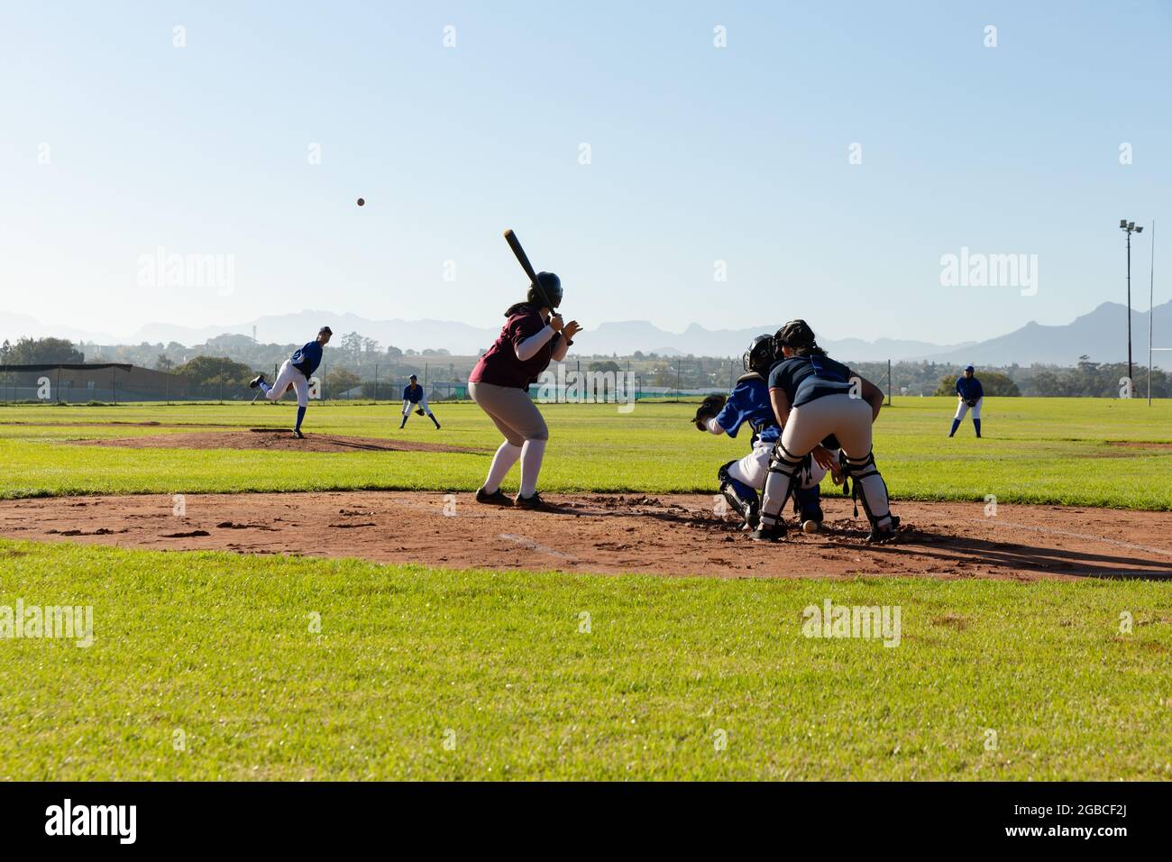 Gruppo vario di giocatori femminili di baseball in azione sul soleggiato campo da baseball durante la partita Foto Stock