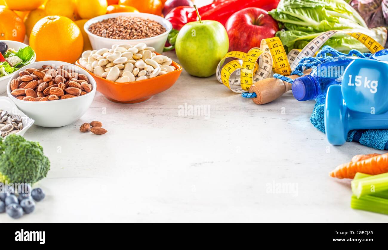 Selezione di alimenti sani, verdure, frutta, mandorle, insalata, attrezzi da esercizio e nastro di misurazione con spazio per la copia. Foto Stock