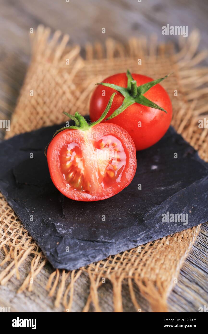 pomodori ciliegini e pomodori a grappolo su fondo rustico in legno Foto Stock