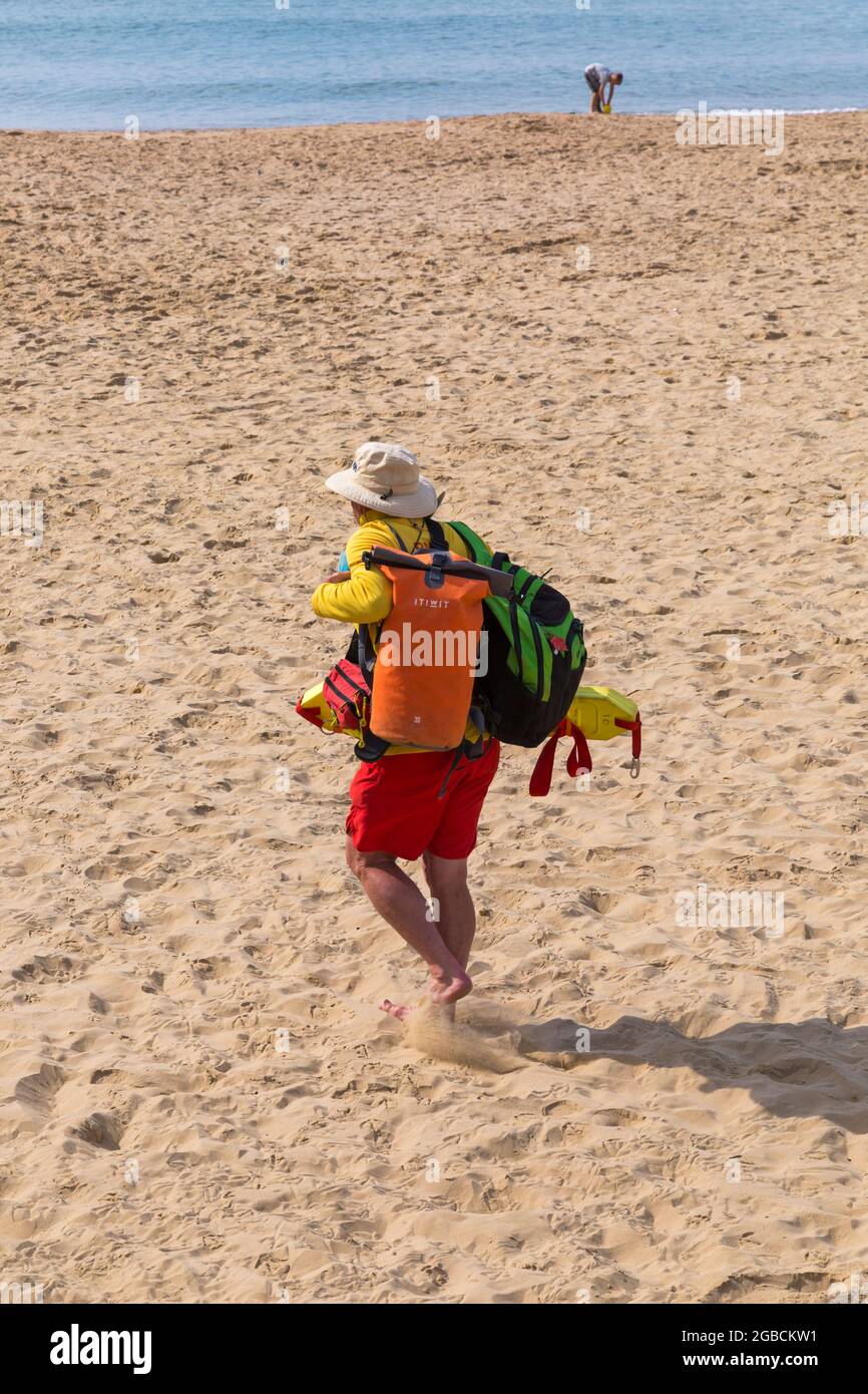 Bagnino RNLI che cammina sulla sabbia a Bournemouth, Dorset UK nel mese di agosto Foto Stock