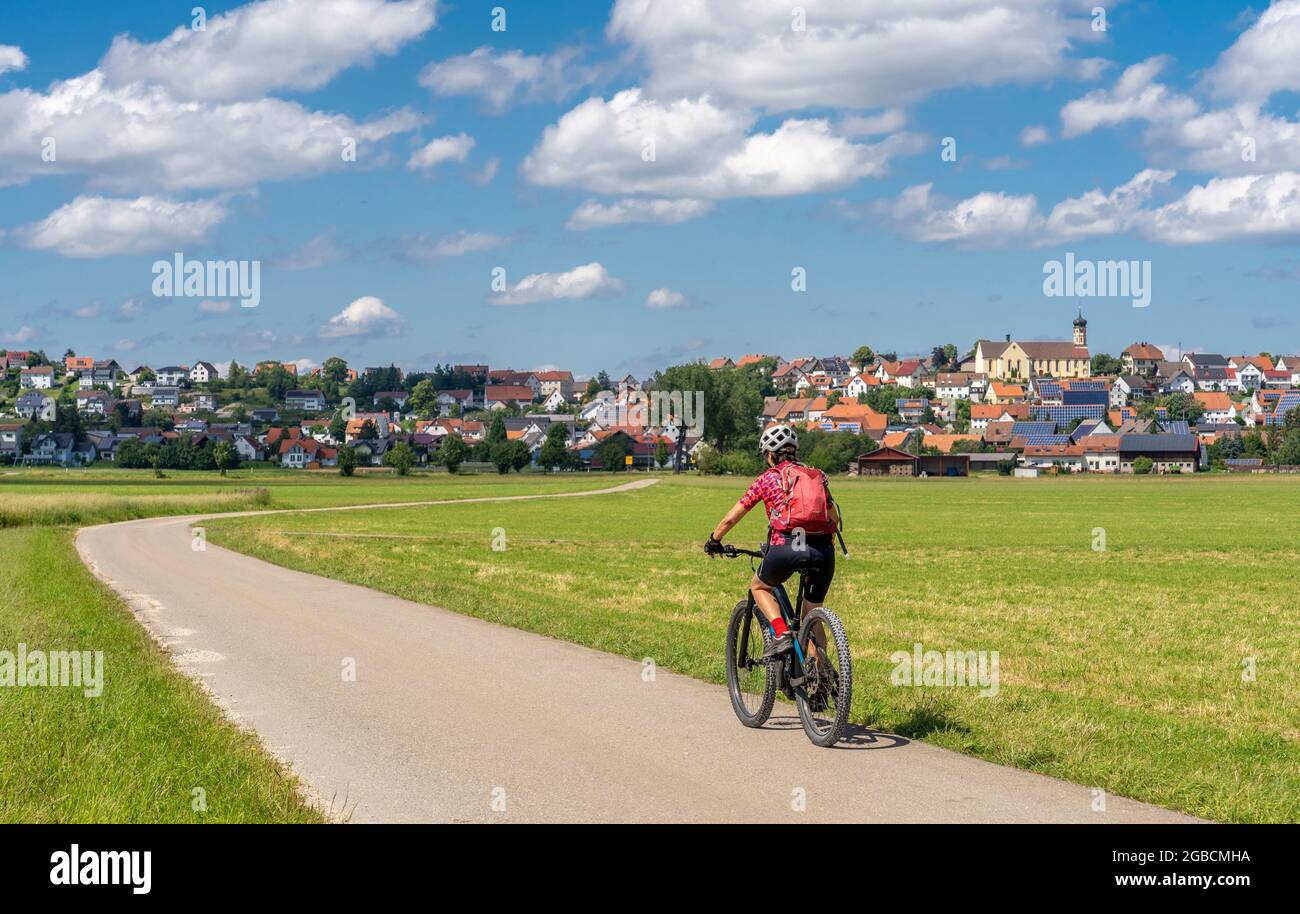 Bella donna attiva in bicicletta con la sua mountain bike elettrica nel sulla Alb Svevo di fronte alla villetta solare di Schwenningen con molti così Foto Stock