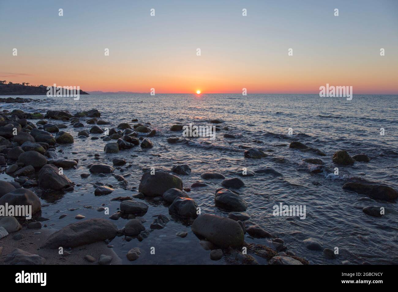 Cefalù, Palermo, Sicilia, Italia. Vista sulle acque tranquille del Mar Tirreno dalla costa rocciosa e dal tramonto. Foto Stock