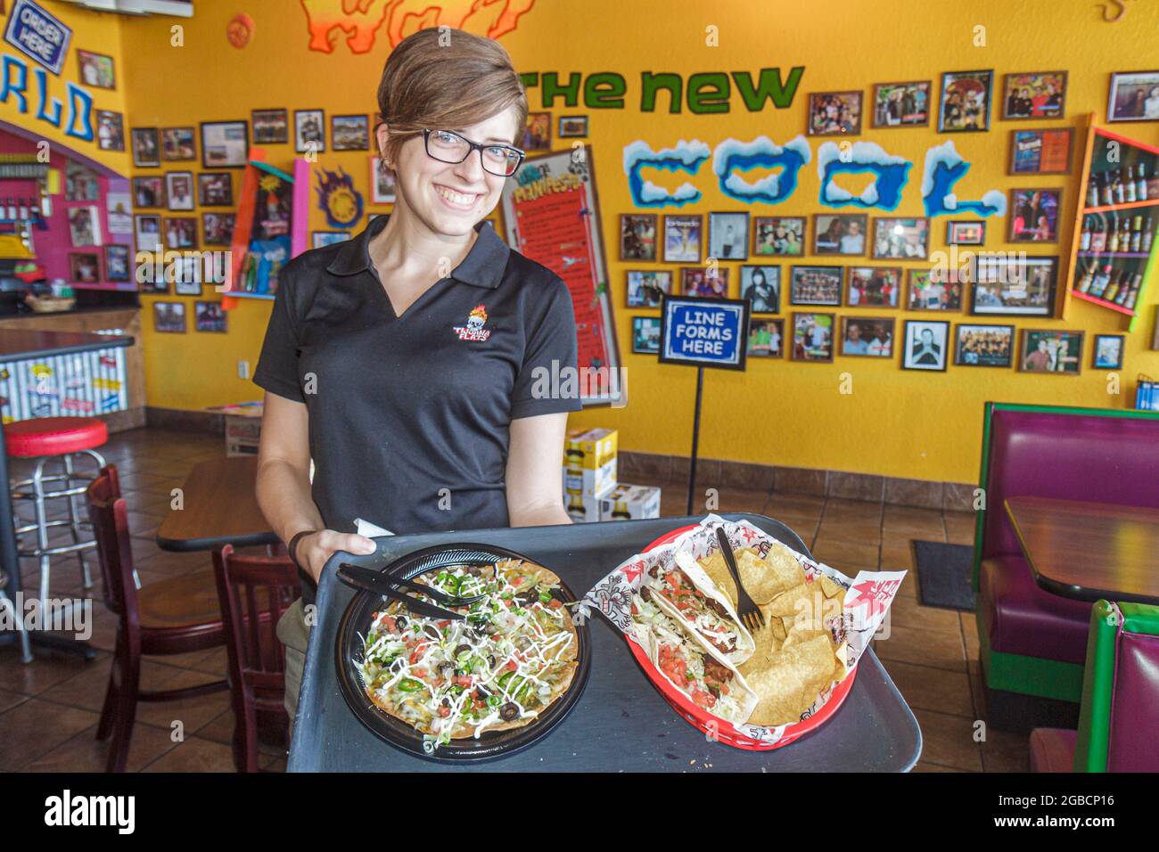 Napoli Florida,Tijuana Appartamenti Tex Mex interno, ristorante cibo donna donna server taco,pizzeria in stile messicano vassoio serving servizio lavoratore Foto Stock