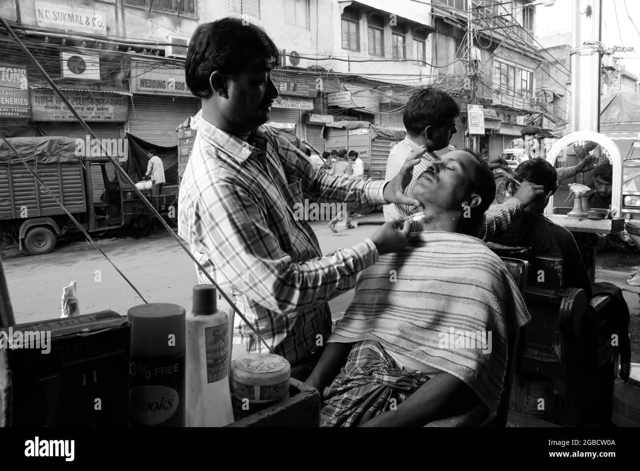 New Delhi, India - 13 marzo 2016: Un barbiere marciapiede dà una rasatura ad un cliente a Nuova delhi, India. E 'comune in tutta l'India per gli uomini di ottenere haircu Foto Stock