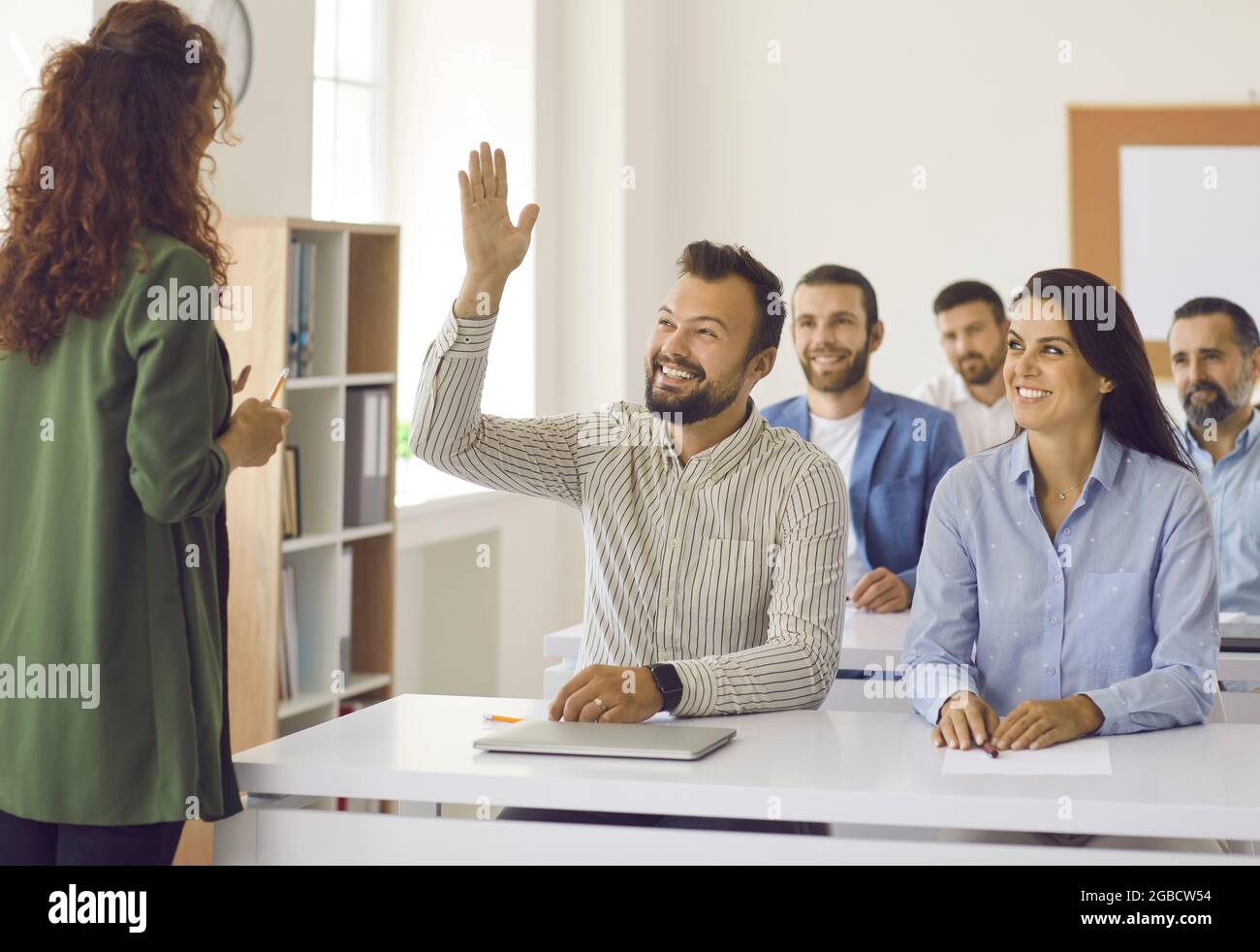 L'uomo felice alza la mano per fare alla vettura alcune domande durante la classe di formazione di affari Foto Stock