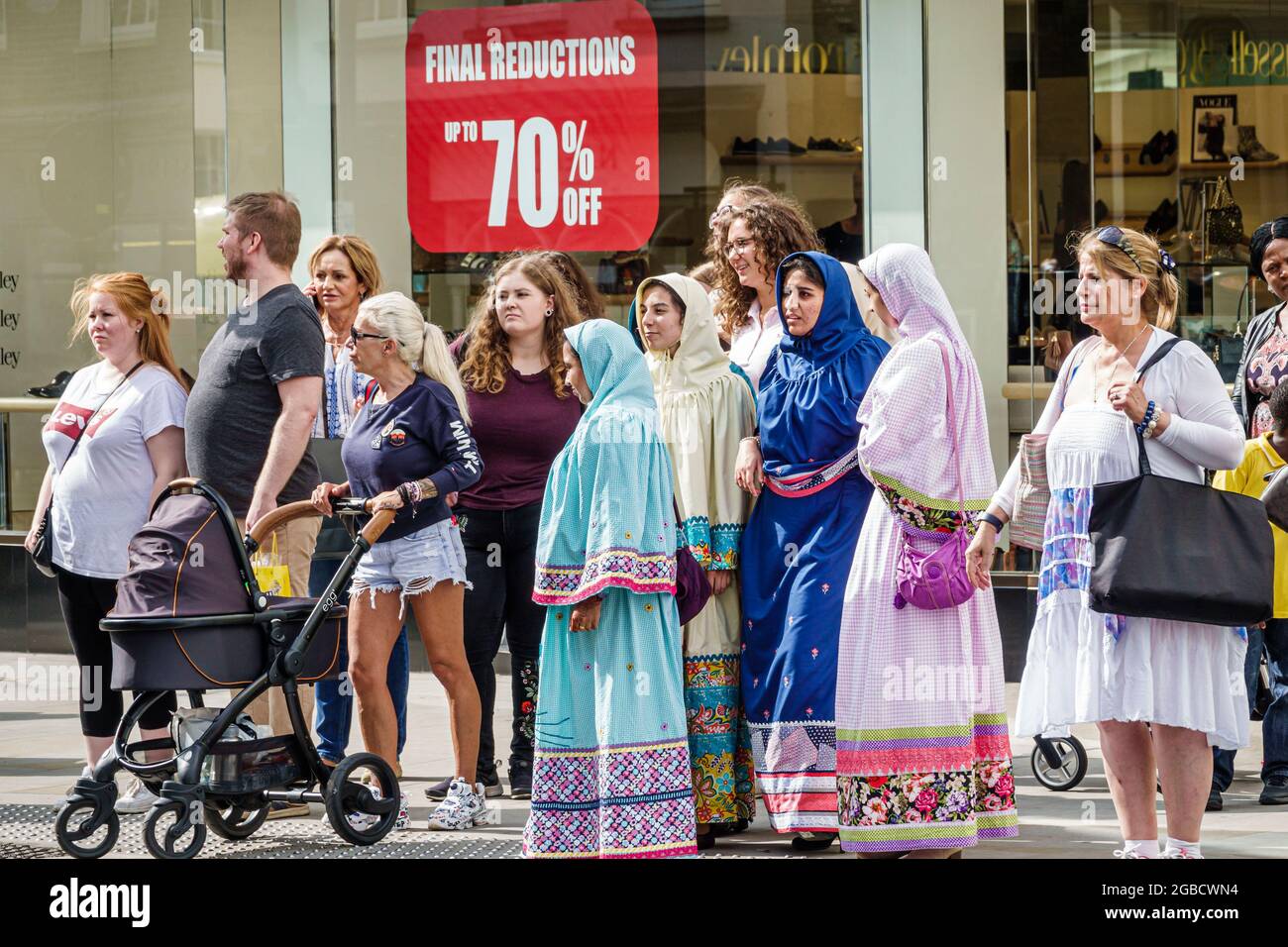 Inghilterra Londra Mayfair New Bond Street, strada angolo pedonale attraversamento attesa segnale, donne musulmana testa coperta, Regno Unito, Foto Stock