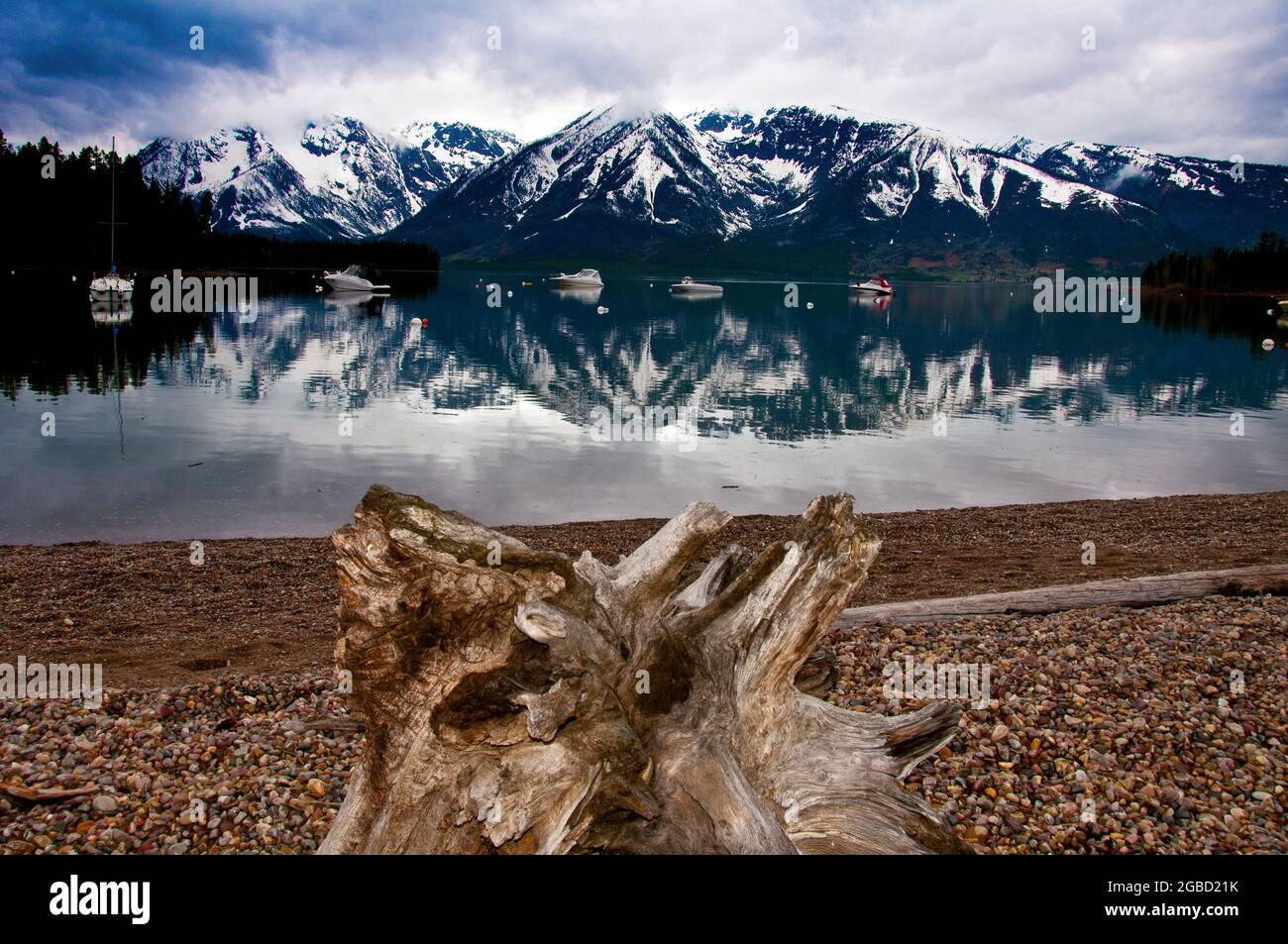 Jackson Lake, innevati Grand Teton riflessi in acqua, barche ormeggiate in acqua a Leeks Marina, Grand Teton National Park, Wyoming Foto Stock