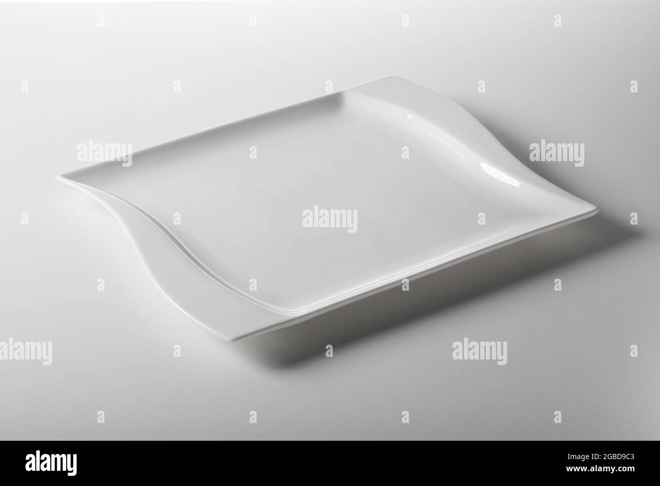 Dall'alto della piastra rettangolare pulita in ceramica con linee ondulate poste su sfondo bianco Foto Stock