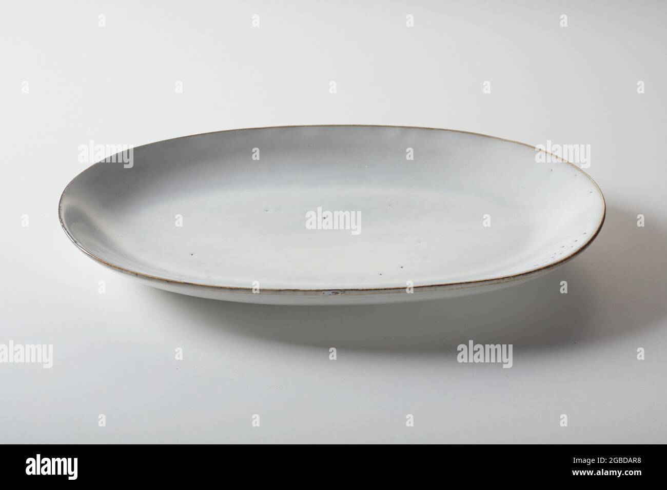 Alto angolo di ceramica ovale forma piatto servito su sfondo bianco in cucina Foto Stock