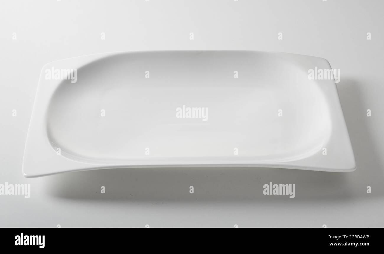 Dall'alto di ceramica pulito piatto rettangolare servito su sfondo bianco in cucina Foto Stock