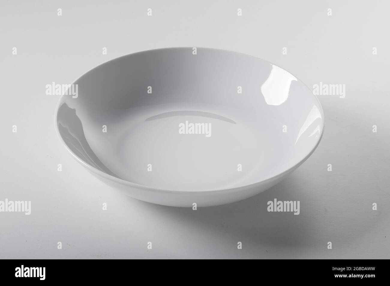 Angolo alto di ciotola vuota pulita di forma rotonda posta su sfondo bianco in cucina Foto Stock