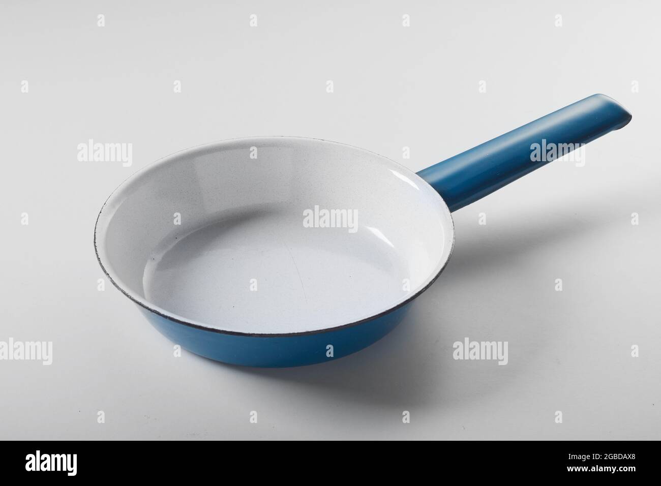 Angolo alto della nuova padella in smalto blu posta su sfondo bianco in cucina Foto Stock