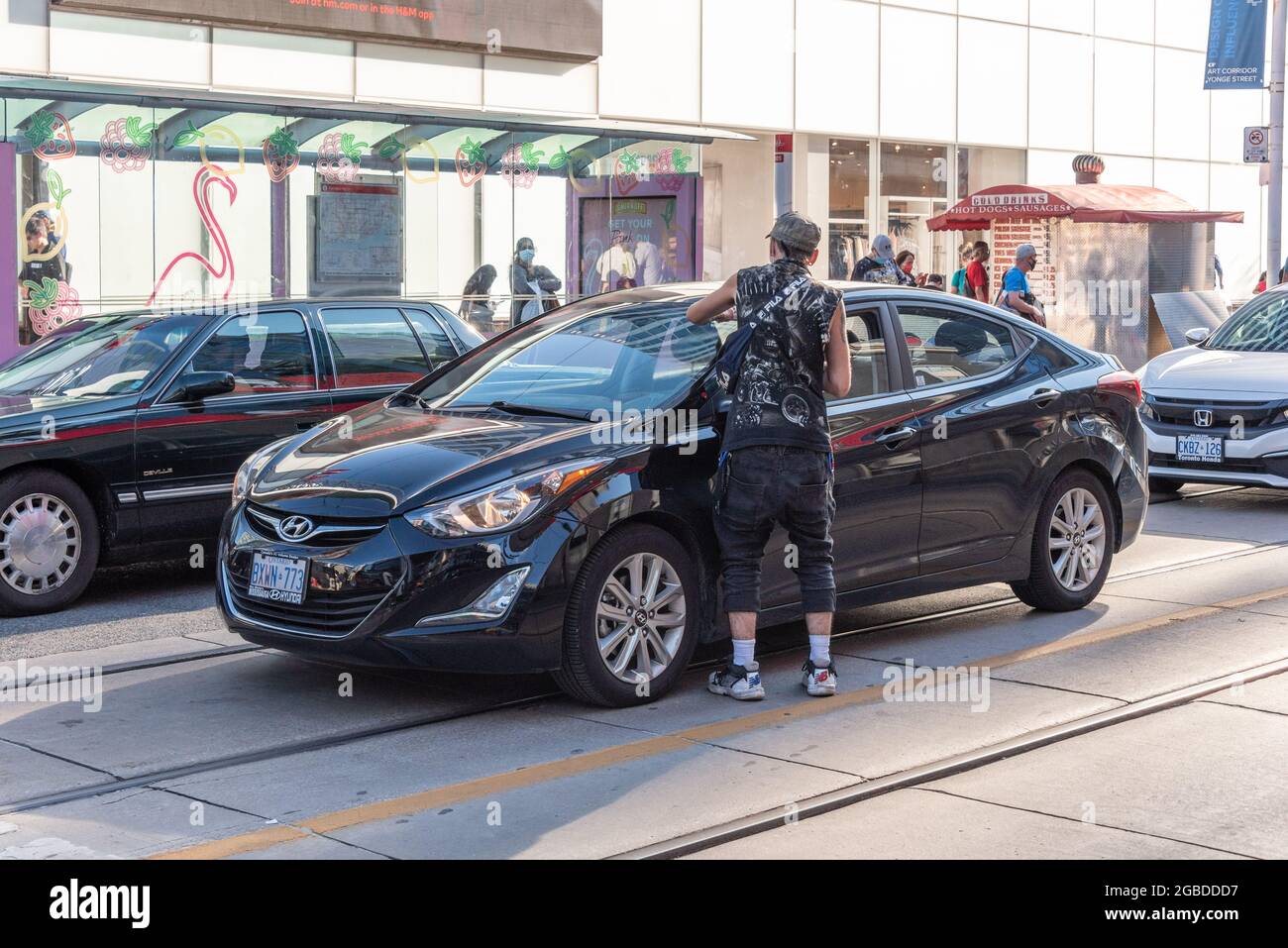Un uomo che pulisce i parabrezza di automobili in Yonge e Dundas Street intersezione nel quartiere del centro di Toronto città, Canada Foto Stock