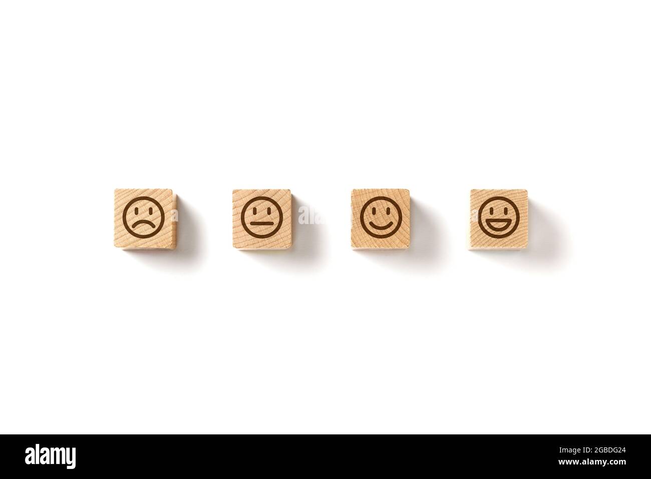 Emoticon facce in blocchi di legno su sfondo bianco. Valutazione del servizio e analisi della soddisfazione. Arrabbiato, neutro, buon umore e felice. Copia Foto Stock