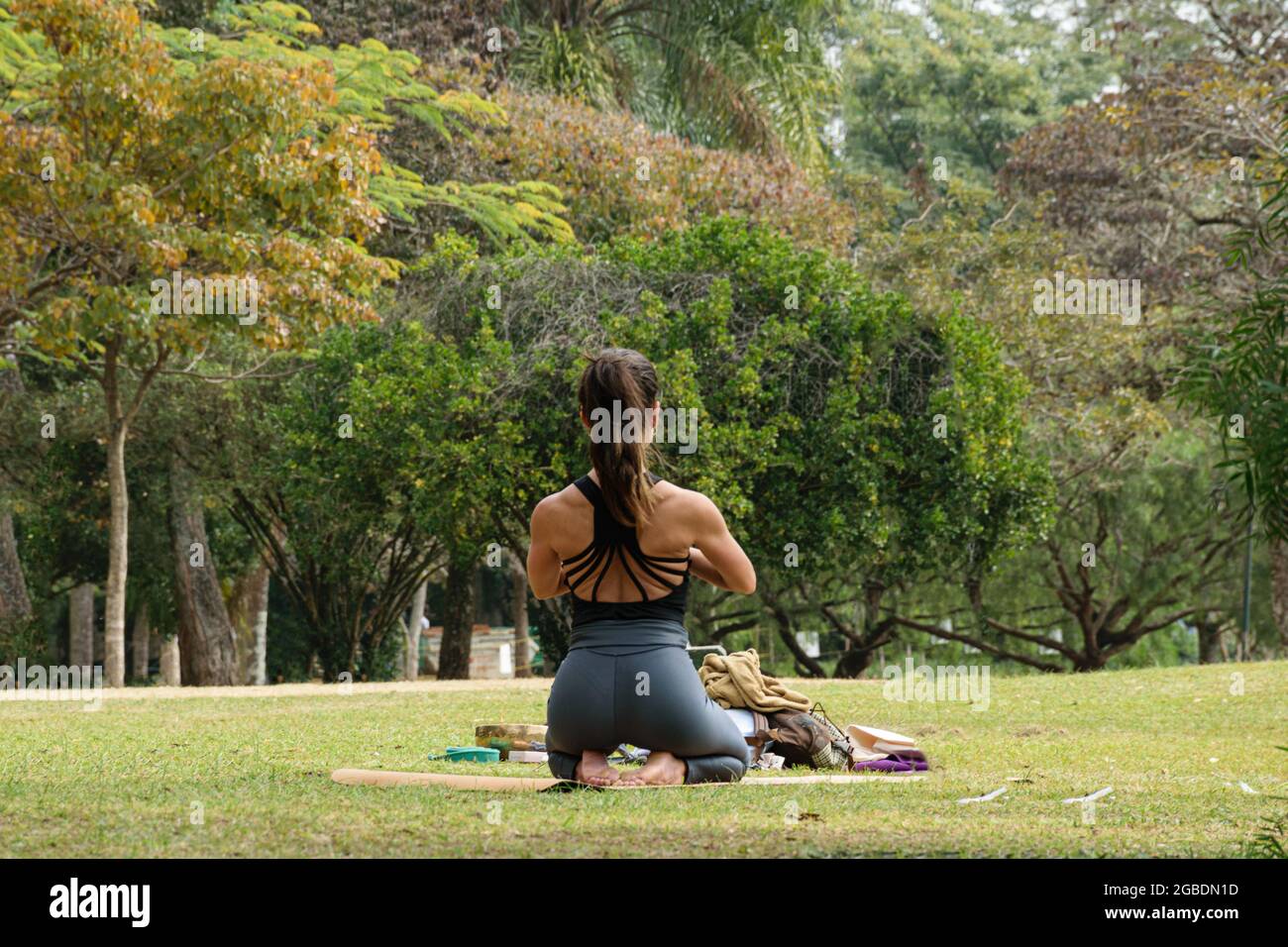 San Paolo, SP, Brasile, luglio 16 2021. donna di 40 anni con schiena strappata seduta sui piedi in una posizione yoga in un parco pubblico. Foto Stock