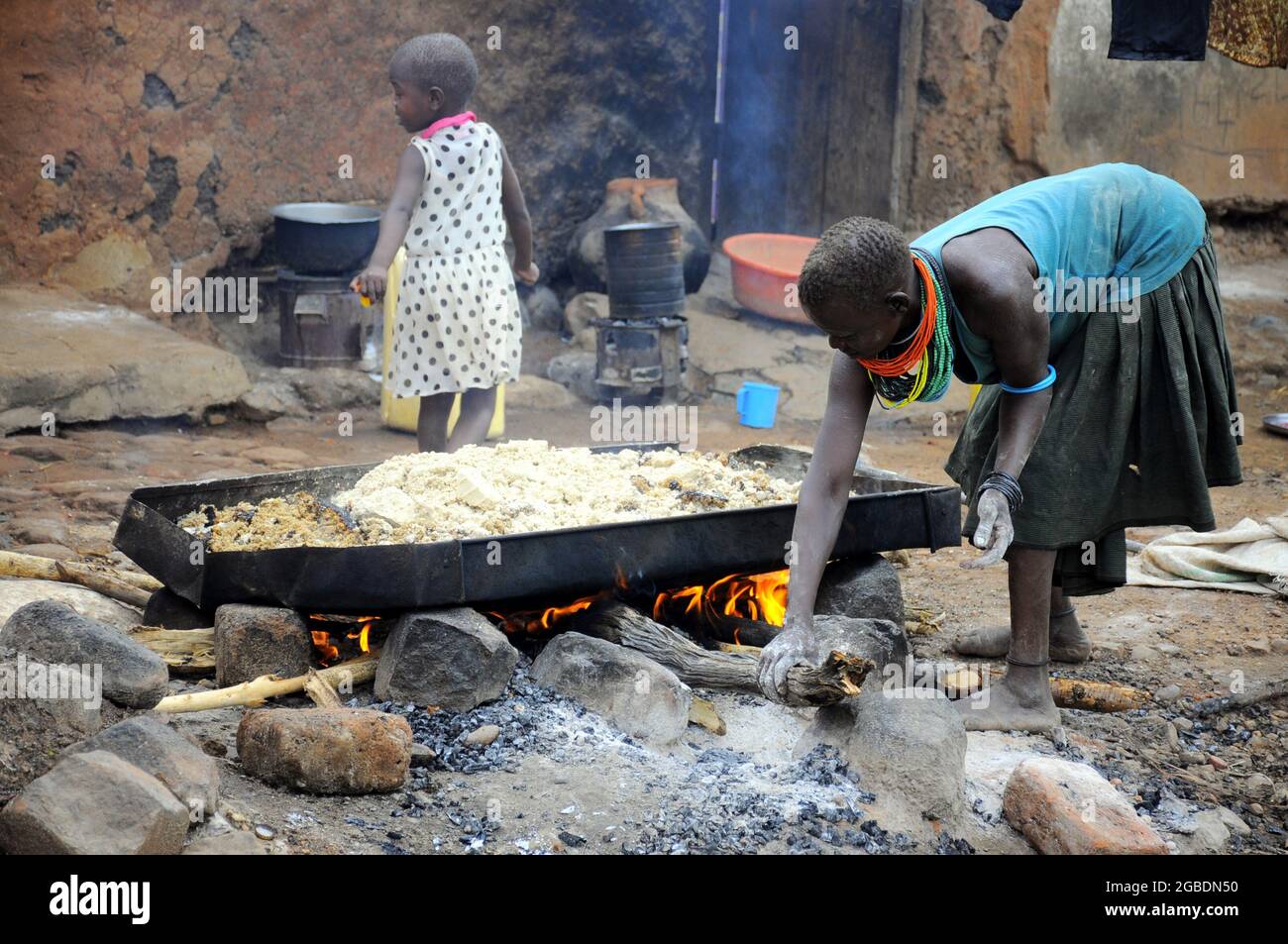 Una donna che arrostiscono la farina di mais dove produce birra locale come fonte di reddito nella regione di Karamoja, nella parte orientale dell'Uganda. In passato il popolo Karamejong dipendeva dal bestiame come fonte di reddito. Uganda. Foto Stock