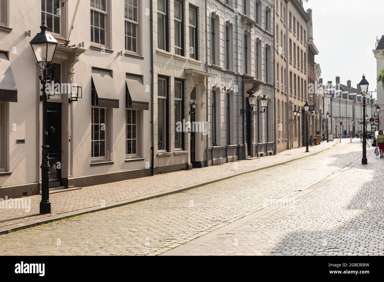 Breda, Paesi Bassi 28 giugno 2021. Strada nel centro della città con vecchi edifici storici con facciate chiare, un marciapiede e lanterne su un soleggiato Foto Stock