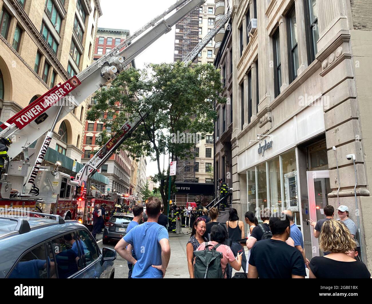 New York, NY, USA - 3 agosto 2021: Le persone che escono dal marciapiede come soccorritori spengono il fuoco nell'edificio vicino Foto Stock
