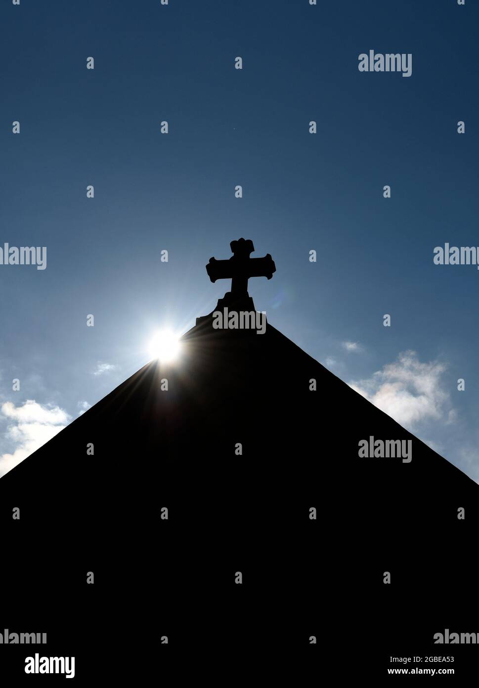Il sole sorge dietro una croce di pietra sulla cima della storica Basilica Cattedrale di San Francesco d'Assisi a Santa Fe, New Mexico. Foto Stock