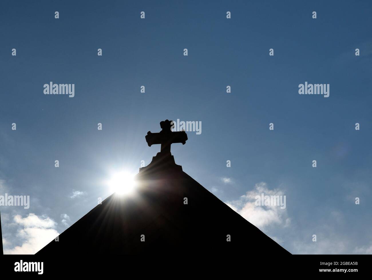 Il sole sorge dietro una croce di pietra sulla cima della storica Basilica Cattedrale di San Francesco d'Assisi a Santa Fe, New Mexico. Foto Stock