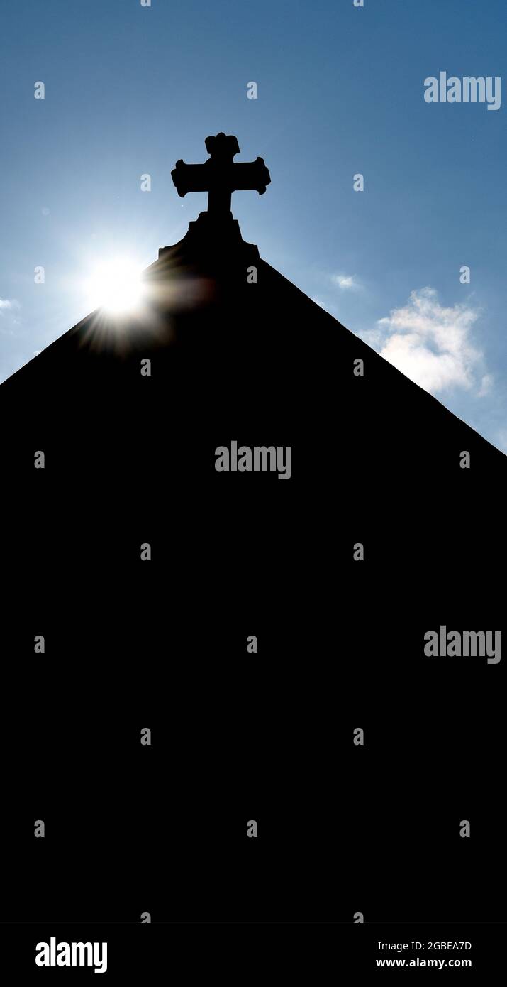 Il sole sorge dietro una croce di pietra sulla cima della storica Basilica Cattedrale di San Francesco d'Assisi a Santa Fe, New Mexico. Foto Stock