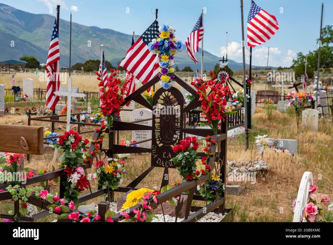 Cerro, New Mexico - un cimitero rurale dove le tombe sono decorate con fiori e bandiere. Foto Stock