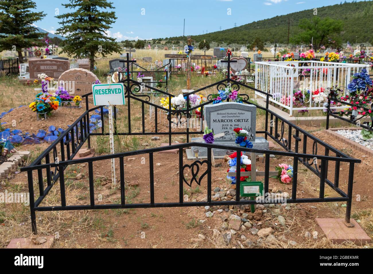 Cerro, New Mexico - un cimitero rurale dove le tombe sono decorate con fiori e bandiere. Un appezzamento di sepoltura è riservato. Foto Stock