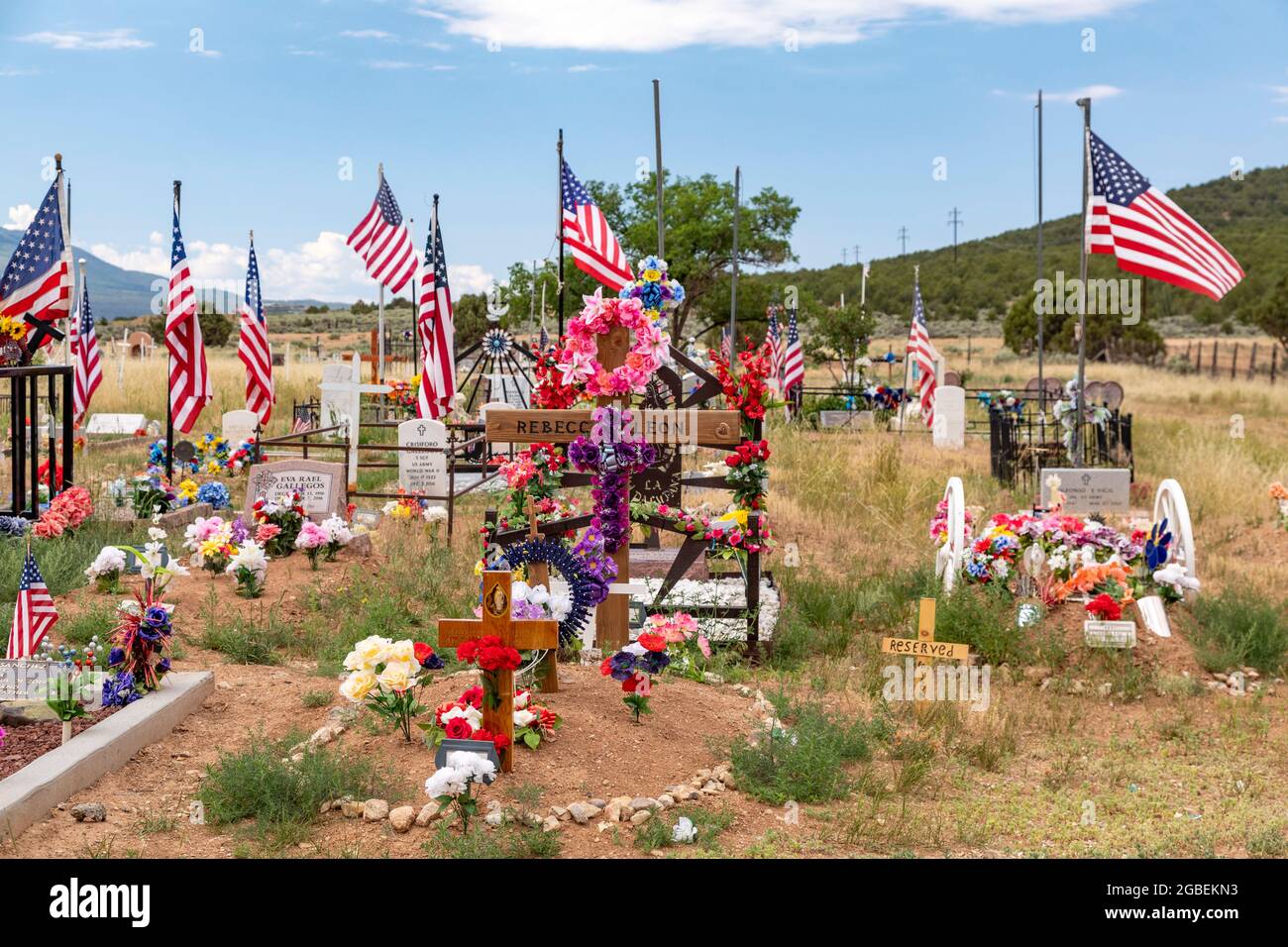Cerro, New Mexico - un cimitero rurale dove le tombe sono decorate con fiori e bandiere. Foto Stock